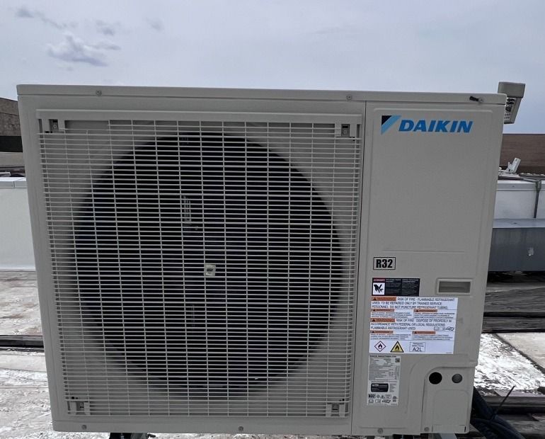 Daikin heat pump condenser set on a rooftop stand
